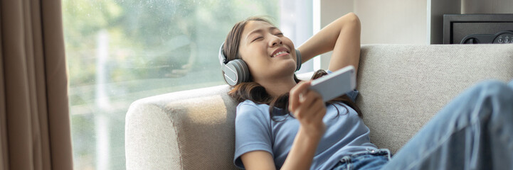 Woman happily listening to music on her favorite sofa in the living room, Relaxation time, Happy...