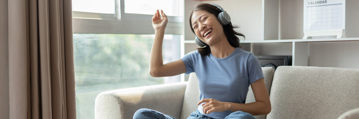 Young Asian woman happily listening to music through headphones, Woman was enjoying listening to...