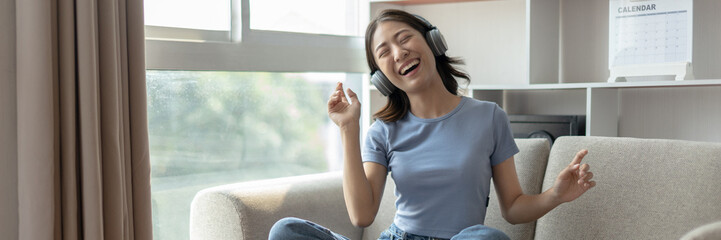 Young Asian woman happily listening to music through headphones, Woman was enjoying listening to...