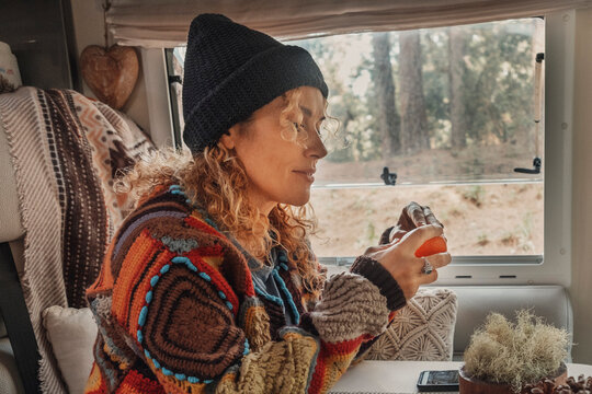 Happy couple enjoy time drinking tea inside a camper van. Nomadic lifestyle tourists people having relax leisure activity inside vehicle motor home. Renting vacation transport. Park outdoors view