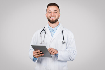 Fototapeta premium Male doctor holding tablet, friendly and professional