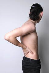 Teenager boy has unhealthy spine, scoliosis, back pain. Naked torso of  boy on light background