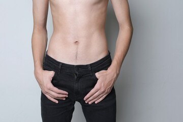 Naked shirtless torso of young guy from the front in jeans