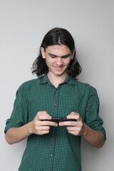 Smiling teen standing and using mobile. Teenager checking apps on mobile device or playing mobile games on the phone.