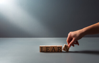 wooden blocks with the word learn , concept of leaning ,adult education , on a blue grey background with copy space .