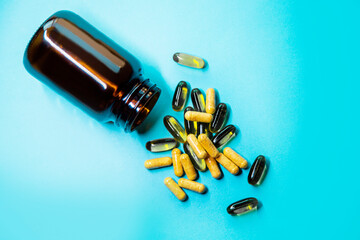 omega-3 capsules and vitamins with lying brown open bottle on a blue background. fish oil tablets...