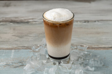 Multilayer iced coffee latte in glass cup on wooden table