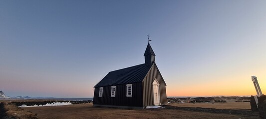 Black Budir church in Iceland (Budakirkja) against a scenic sunset