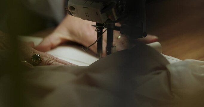 Closeup shot of female hands working with a sewing machine and fabric