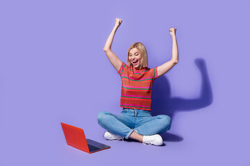 Full body photo amazed addicted player woman raises fists up win one million dollar in online casino isolated over purple color background