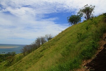 Scenic shot of grass-covered green hills with clouds covering the blue sky