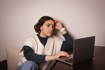 student girl using laptop at home working and studying online. A serious and thoughtful woman thinking about new projects
