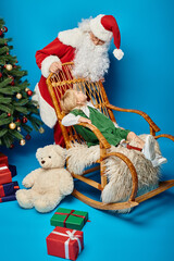 Santa Claus rocking chair with cute girl with prosthetic leg next to teddy bear and Christmas tree