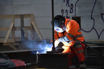 Man in a work suit and with a helmet, welding at the construction site of Vienna's metro - obrazy, fototapety, plakaty