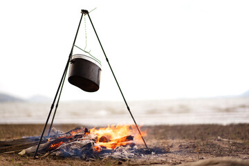 Boiling water in a small metal camping kettle - bowl on burning firewood.