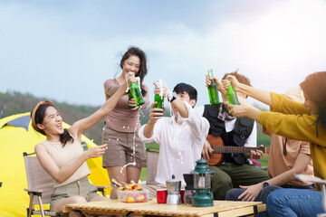 Asian young women and men celebrating with a bottle of a beer together.