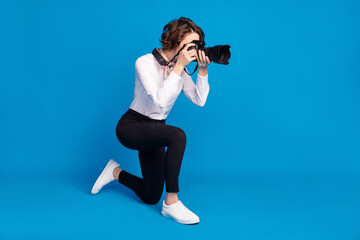 Full size profile portrait of paparazzi stand on knee making photos isolated on blue color background