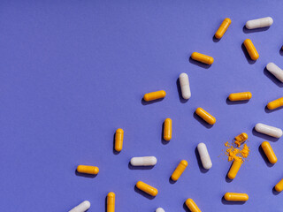 Top view pattern orange and white vitamin pills on violet background