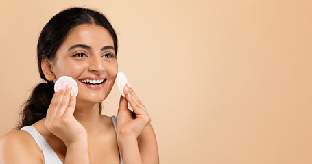 Obraz na płótnie Canvas Facial Beauty Treatment. Happy Indian Woman Using Cotton Pad For Cleansing Face