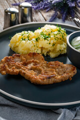 Pork chop served with mashed potatoes and cucumber salad.