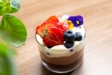 Chocolate mousse dessert in a glass cup decorated with fresh fruits, top view, selective focus, with blurred background.