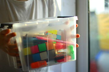 the child holds a box with educational games, puzzles, pencils. preparation for a creative activity