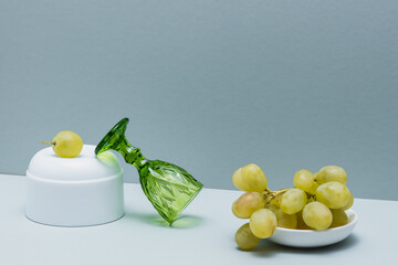 A dish with light grapes and an empty green wine glass.