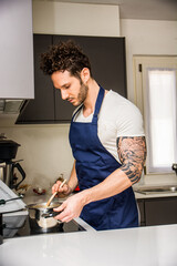 A man in an apron is cooking in a kitchen. A Skillful Chef Preparing a Delicious Meal in a Modern Kitchen