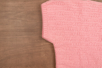 Warm winter knitted pink wool sweater on a wooden background