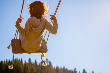 Young girl flying on swing. Happy childhood, freedom concept. Copy space.