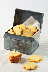Homemade butter cookies inside a tin, on white background.