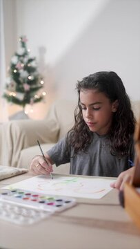 Latin child boy painting with watercolors during Christmas time at home. Holiday vacations