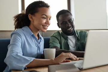 Obraz premium Young colleagues working online on laptop in coffee shop