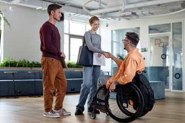 Colleagues greeting each other while having meeting in office hall