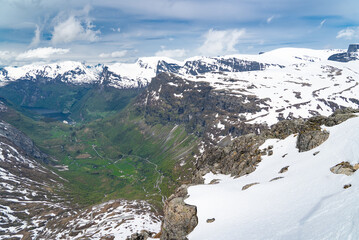 On top of Dalsnibba, Geiranger's Skywalk with views over the snow-capped mountains and the village of Geiranger down in the valley - 678780591