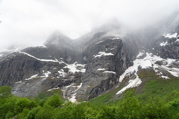 Cloud-covered Troll Wall above the Rauma River near Andalsnes, Norway - 678780593