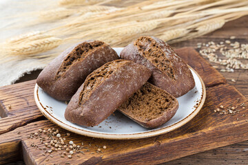 Crispy rye bun on a plate, wooden background