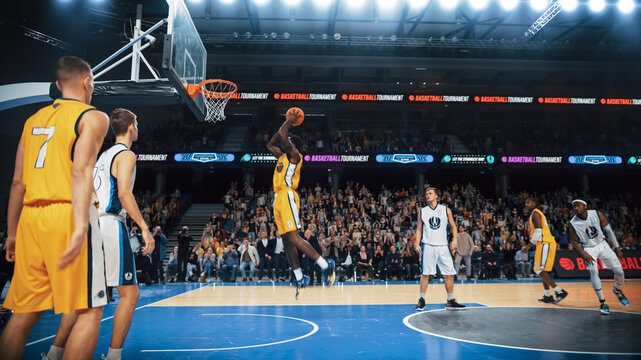 Cinematic College Basketball Tournament: Two Young Successful Diverse Teams Play a Championship Match in a Modern Arena. Excited African Player Scores a Beautiful Goal by Slam Dunk with Two Hands.