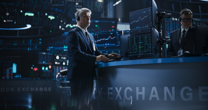 Handsome Middle Aged Stock Exchange Trader Following a Live Auction, Communicating Buy and Sell Orders to Operator on the Other Side of the Call. Professional Investment Banker at Work