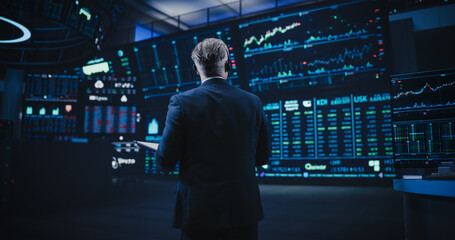 Back View of a Middle Aged Stock Exchange Trader Following a Live Auction, Communicating Buy and...