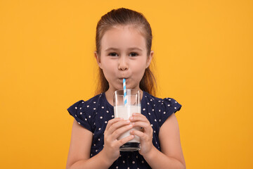Cute girl drinking fresh milk from glass on orange background - obrazy, fototapety, plakaty