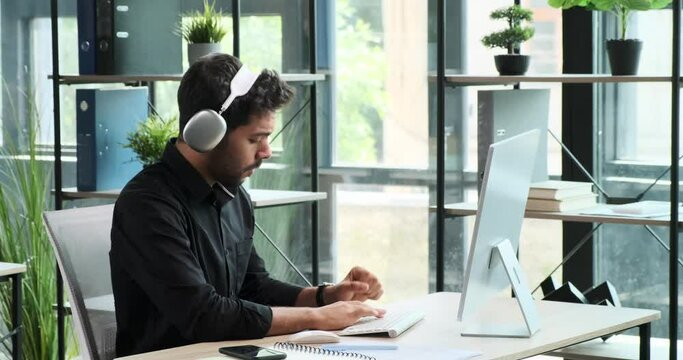 Middle Eastern man sits comfortably on a sofa, typing on his laptop with focused determination. His adaptable work environment reflects the versatility of modern professionals.