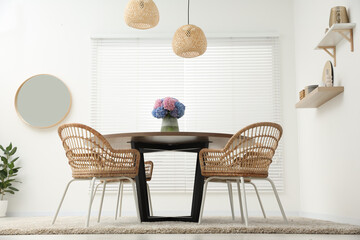 Table, chairs and vase of hydrangea flowers in dining room, low angle view. Stylish interior