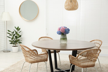 Table, chairs and vase of hydrangea flowers in dining room. Stylish interior