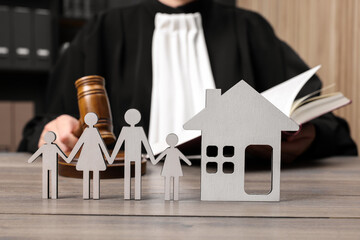 Family law. Judge with gavel and book sitting at wooden table, focus on figures of parents,...