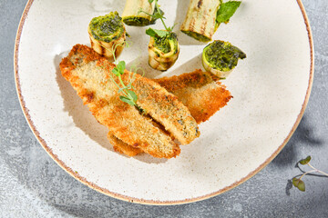 Macro shot from a top view angle of grilled perch and zucchini rolls. Every detail pops, from the grill marks to the sauce droplets, against the gray concrete background