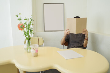 woman covering her face with blank book or magazine in mock up concept.