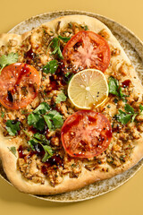 An appetizing Turkish Lahmacun pizza with shrimp and fresh tomato slices, garnished with parsley and lemon, served on a stone plate