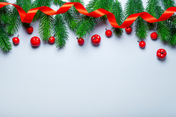 Christmas card with copy space - fir branches and red New Year decorations on a light blue background