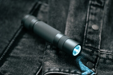 Pocket flashlight for Everyday Carry (EDC) on a dark background. Ray of light.	
